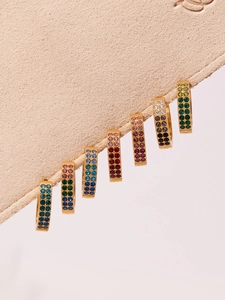 Detailed macro view of seven pairs of double-row pavé zircon hoop earrings in various colors