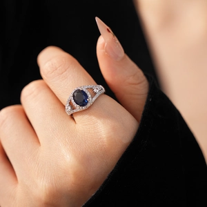 Close-up of geometric silver ring featuring a large oval blue zircon and pavé diamonds