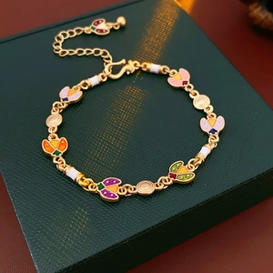 Détail du bracelet vintage doré avec breloques papillon en émail sur boîte verte