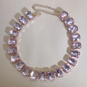 Detailed close-up of sparkling pink rectangular crystal gemstone necklace with gold chain