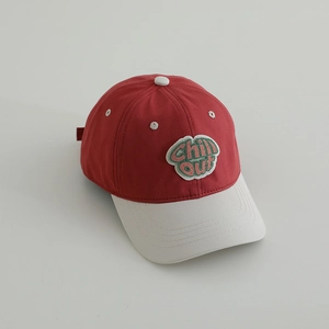 Detail of red and beige baseball cap featuring embroidered 'Chill Out' patch and eyelets
