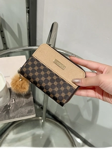 Detail of luxury brown floral short wallet with metal tag and plush ball accessory
