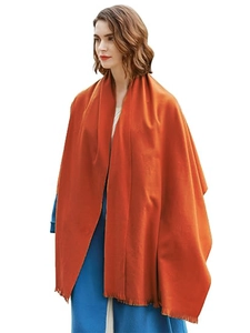 Close-up of bright orange cashmere-feel scarf with soft fringe tassels on a blue coat