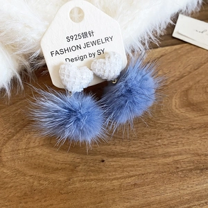 Dettaglio di orecchini a cuore in tweed con pompon in ecopelliccia blu su cartoncino