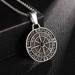 Macro shot of silver compass pendant with black gemstone on textured dark leather