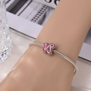 Pink enamel Capricorn zodiac charm on a silver snake chain bracelet worn on wrist