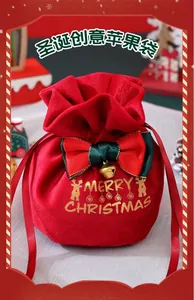 Detail of red velvet Christmas gift bag with gold elk print and ribbon bow with bell