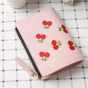 Detail of pink pebbled leather wallet with cherry embroidery and gold hardware