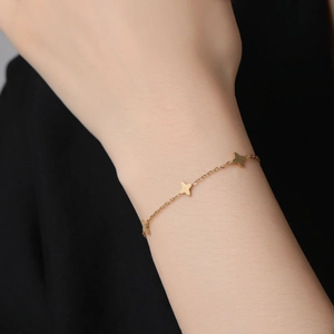 Bracelet élégant à double couche avec trèfle à quatre feuilles en or sur poignet féminin