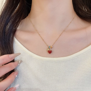 Detailed view of an 18k gold plated necklace with a red heart pendant and colorful rings
