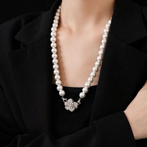 Elegant pearl necklace featuring a zircon encrusted flower pendant on black suit jacket