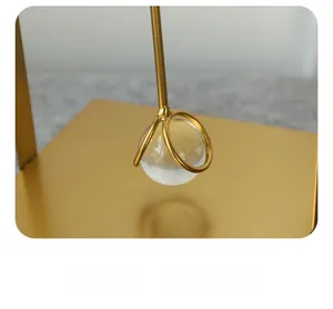 Close-up of golden iron napkin holder featuring a polished glass sphere and matte texture
