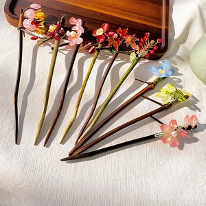 Detailed close-up of various Chinese wood hair sticks with resin flowers and pearls