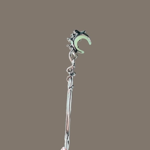 Détail de l'épingle à cheveux lune argentée avec incrustation verte luminescente