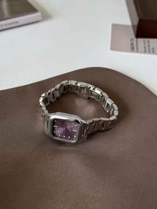 Detailaufnahme der eckigen silbernen Damenuhr mit lila Zifferblatt auf braunem Tisch
