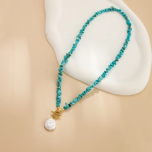 Macro shot of turquoise stone necklace with baroque pearl pendant and golden OT clasp