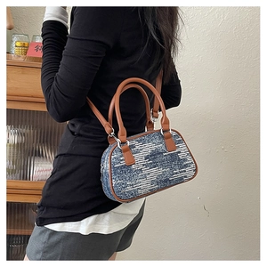 Detailed view of sequin wave patterns on a denim pillow bag with brown leather handles