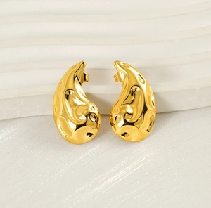 Macro shot of gold-plated teardrop stud earrings with hammered texture and polished finish