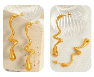 Detail of gold wavy earrings with modern abstract curved design and glossy metal finish