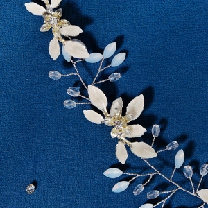 Dettaglio macro della vite da sposa dorata con foglie di opale e fiori di strass