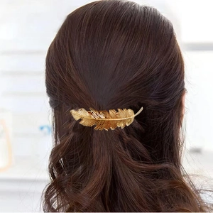 Vintage golden feather metal hair clip with detailed leaf texture on brunette wavy hair