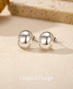 Detail shot of minimalist silver bean earrings with smooth mirror finish on textured stone