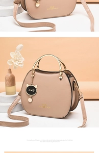Detail of apricot PU leather shell bag with gold handle and cute cat pendant charm