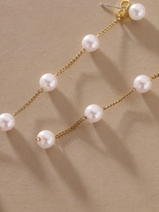 Detailed macro view of elegant long gold tassel earrings with lustrous white pearls