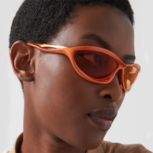 Close-up of orange futuristic Y2K sports sunglasses with curved wrap-around frame design
