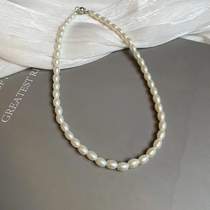 Detailed close-up of white pearl necklace with metallic clasp on silk fabric
