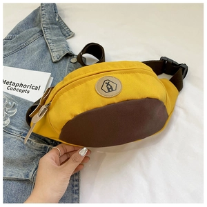 Detail of canvas chest bag featuring yellow and brown color blocking with XH logo patch