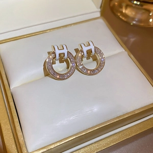 Close-up of gold-plated H-letter earrings with sparkling cubic zirconia in a jewelry box