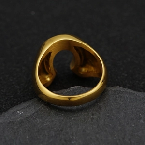 Close-up of a gold U-shaped horseshoe ring placed on a textured dark grey stone surface