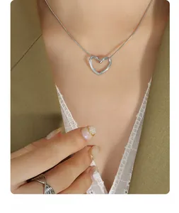Close-up of silver heart pendant snake chain necklace and twisted ring on a model