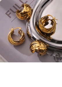 Macro detail of gold-plated titanium steel hoop earrings with twisted spiral texture