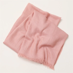 Detailed texture of pink cotton linen scarf with natural pleats and frayed tassel edges