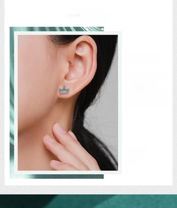 Close-up of crown-shaped silver stud earring with blue gems worn by a female model
