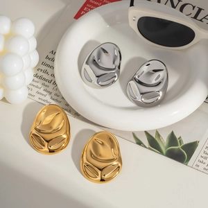 Detail of 18K gold plated and silver irregular oval earrings with embossed face designs