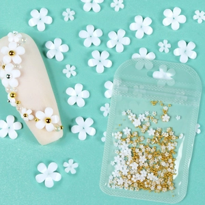 Close-up of 3D white resin flowers and gold silver beads for DIY nail art design