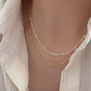 Detail of paperclip chain necklaces in gold and silver finish worn by a model