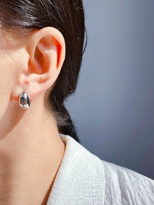 Close-up of a minimalist silver teardrop earring worn for a sleek and modern aesthetic