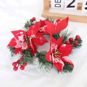 Detail of frosted red poinsettia candle ring with cedar needles and snowy red berries