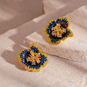 Détail macro de boucles d'oreilles fleurs vintage bleues avec bordure dorée et cristaux