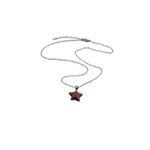 Minimalist silver chain necklace with a reddish brown star-shaped stone pendant on white background