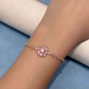Close-up of pink zircon flower bracelet with gold micro-pave chain on wrist