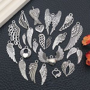 Close-up of vintage silver alloy angel wings and heart charms for DIY jewelry making