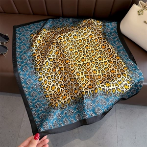 Leopard print square silk scarf in Prussian blue and ginger yellow on a leather surface