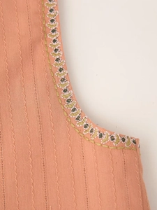 Detailed embroidery on a pink textured fabric vest featuring ethnic patterns and stitching