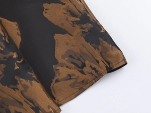 Détail du motif jacquard bronze sur tissu tissé noir pour une robe évasée à taille haute