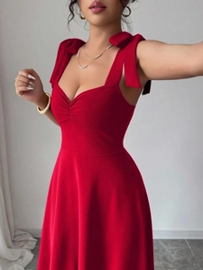 Elegante rode jurk met schouderbandjes met strik en een flatterende hartvormige hals